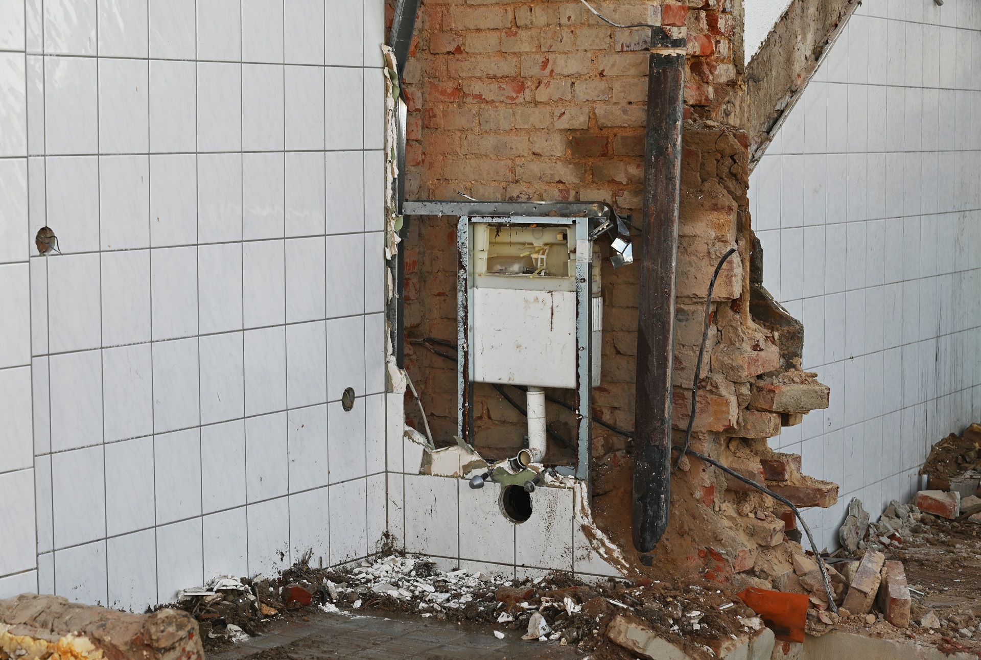 Beschädigte Wand mit freigelegtem Ziegelmauerwerk | Reparaturasphalt